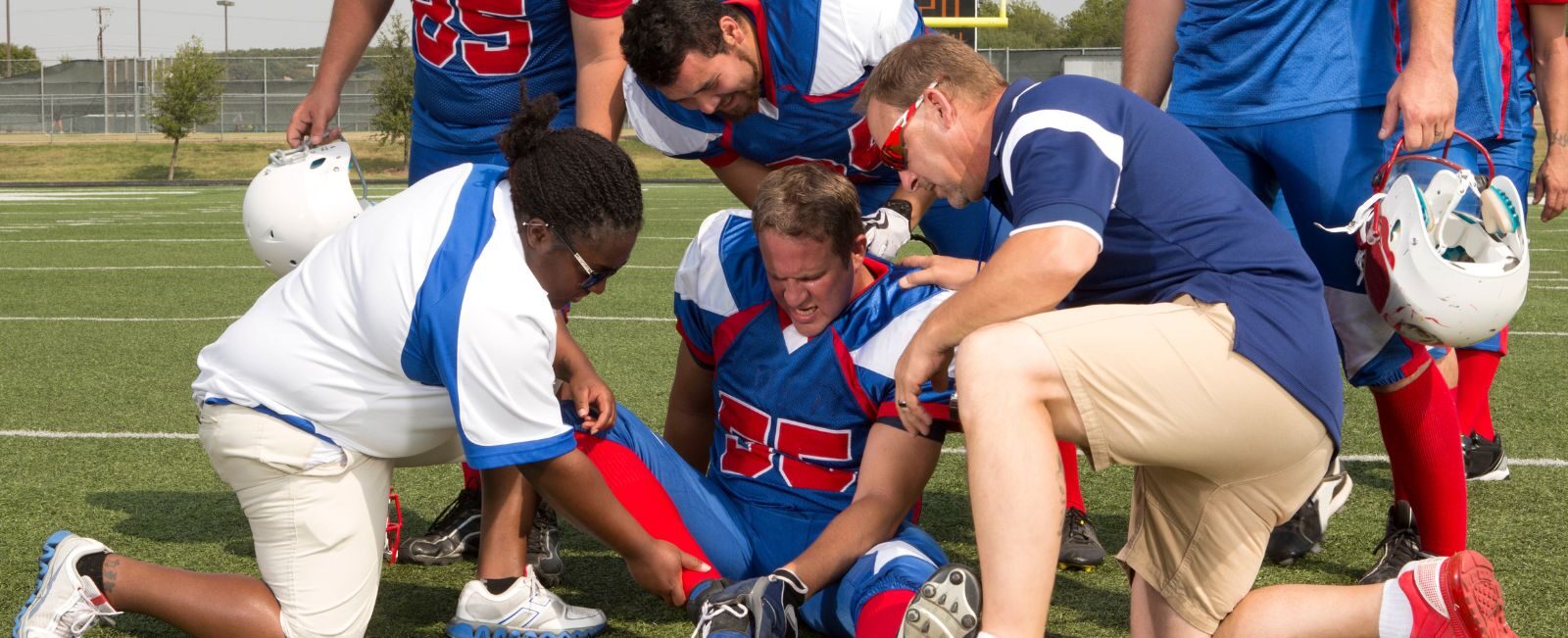 High school football players surround an injured teammate on the field as coaches and trainers assess his knee injury. Genesis Sports Therapy, located at 231 13th Pl NW Suite B, Hickory, NC, specializes in LED light therapy for athletes' rapid recovery and peak performance. The therapy supports quick recovery from sports injuries, allowing athletes to return to the game stronger than before.