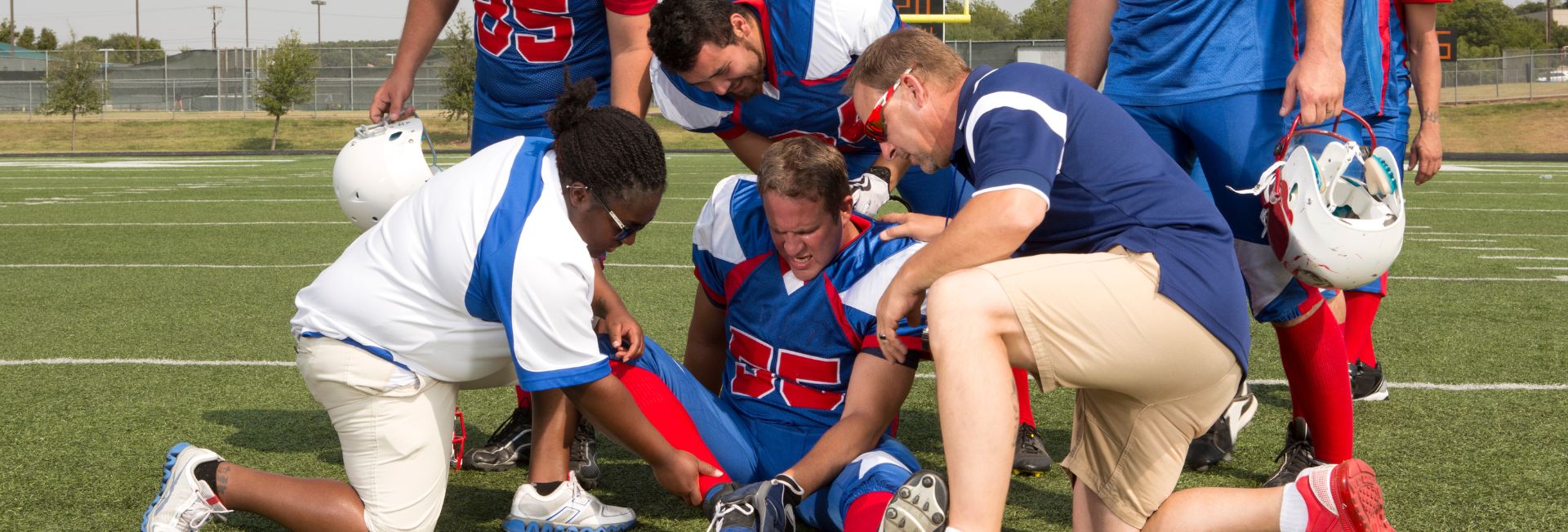 High school football players surround an injured teammate on the field as coaches and trainers assess his knee injury. Genesis Sports Therapy, located at 231 13th Pl NW Suite B, Hickory, NC, specializes in LED light therapy for athletes' rapid recovery and peak performance. The therapy supports quick recovery from sports injuries, allowing athletes to return to the game stronger than before.